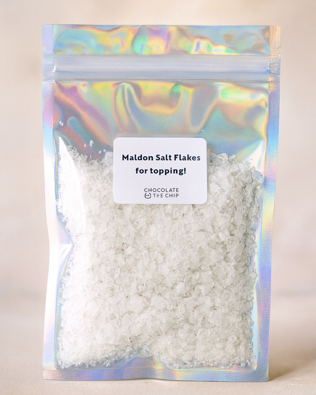 Packaged Maiden Salt Flakes with a colorful reflective label on a neutral background