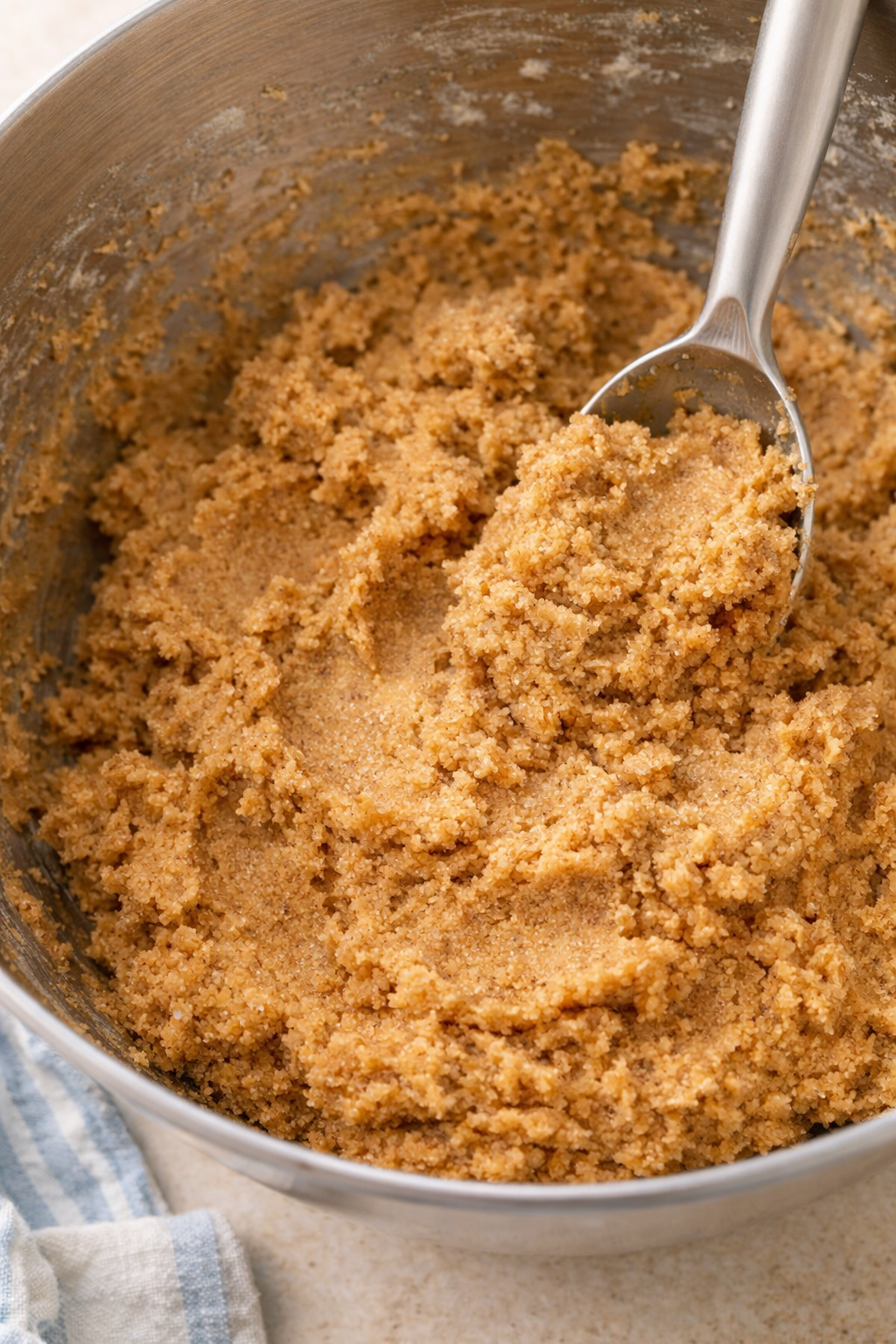Brown cookie dough in a mixing bowl with a spoon