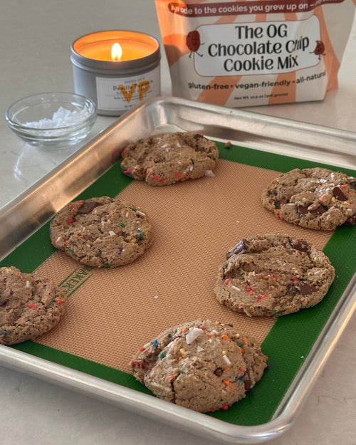 Baked cookies on a baking sheet with a candle and cookie mix package in the background.
