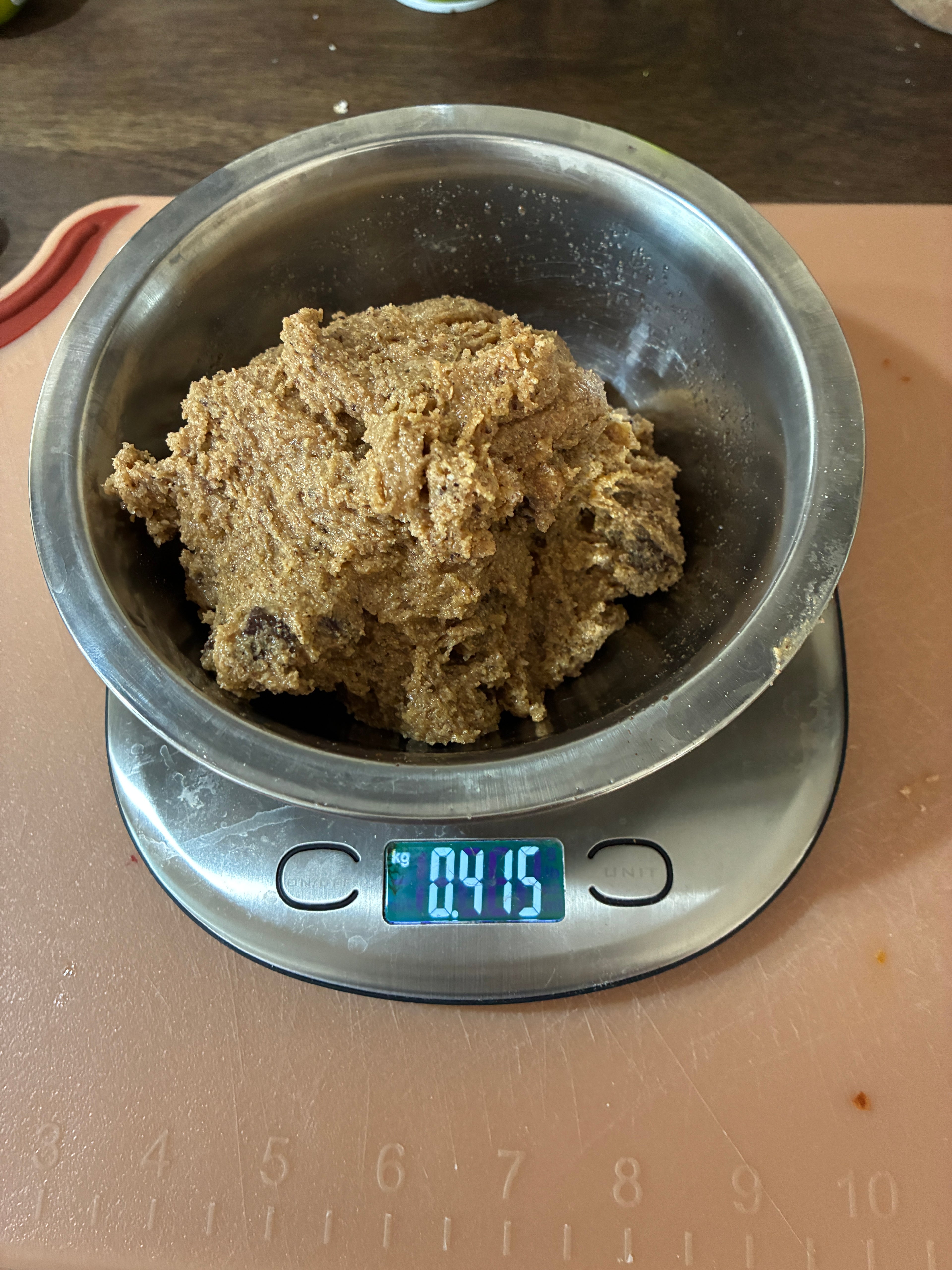 A picture of the cookie dough in a silver bowl on a scale before it's chilled.