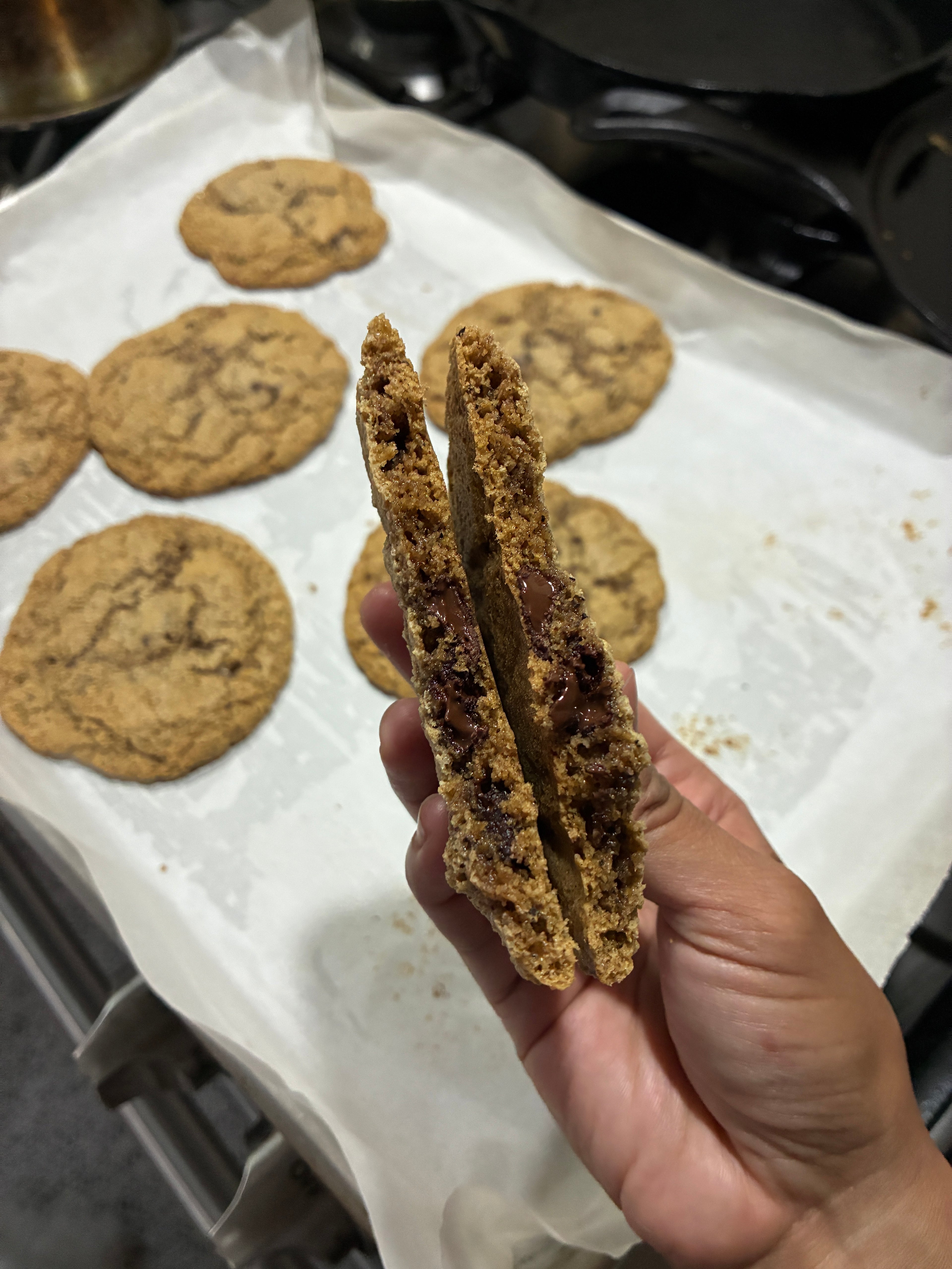 A picture of a freshly baked cookie, cut in half, held in hand.